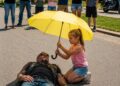 As Everyone Else Stood Back and Filmed a Biker Collapsing Beneath the Scorching Sun, Only One Eight-Year-Old Girl Walked Toward Him With a Yellow Umbrella… Moments Later, the Entire Crowd Witnessed Something They Would Never Forget