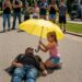 As Everyone Else Stood Back and Filmed a Biker Collapsing Beneath the Scorching Sun, Only One Eight-Year-Old Girl Walked Toward Him With a Yellow Umbrella… Moments Later, the Entire Crowd Witnessed Something They Would Never Forget